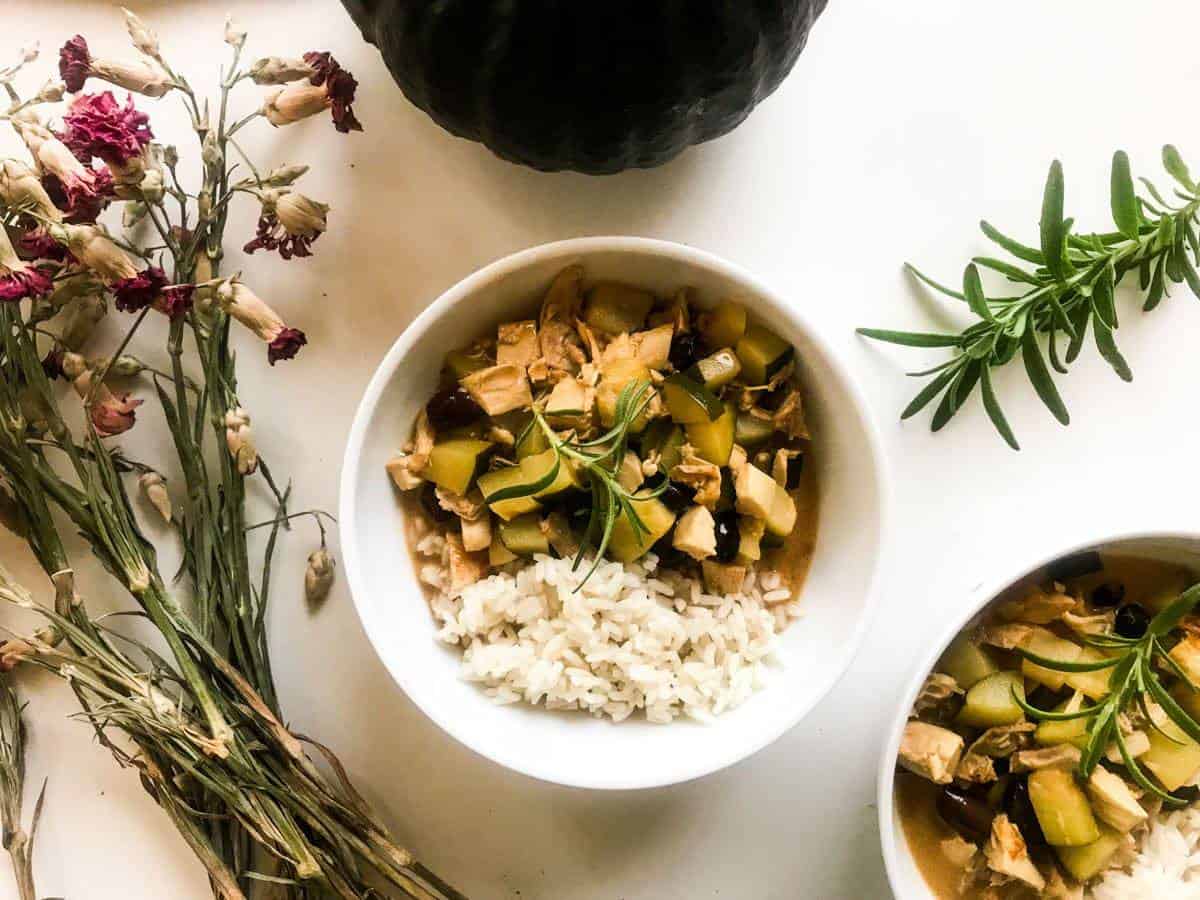 Two bowls of Quick Rosemary Lemon Chicken Stew with rice on a white table decorated with dried flowers and rosemary