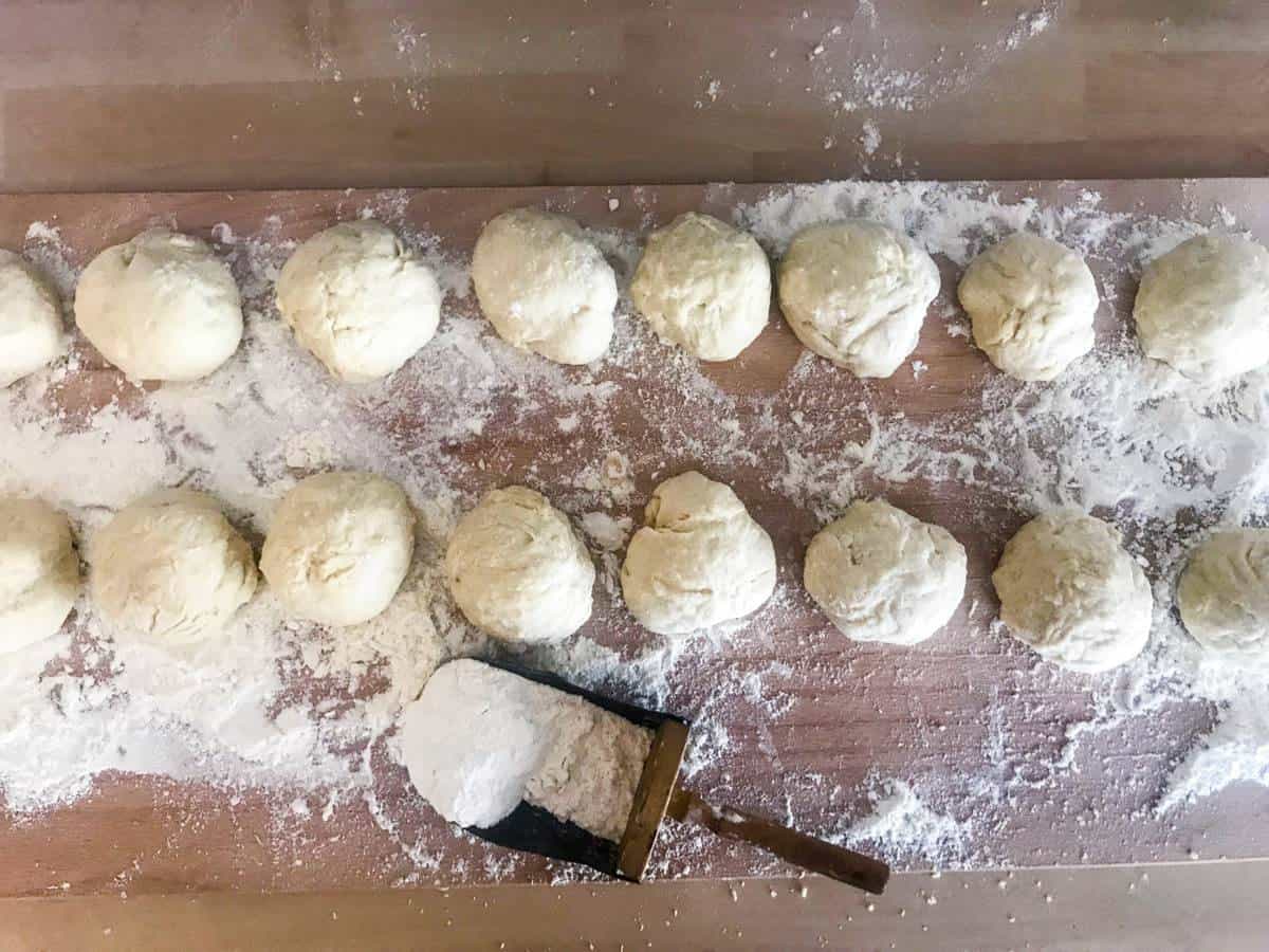 Overnight english muffins with flour on a wooden surface