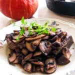 Quick one-pan pork chops and mushrooms with red wine and thyme in a black cast iron skillet