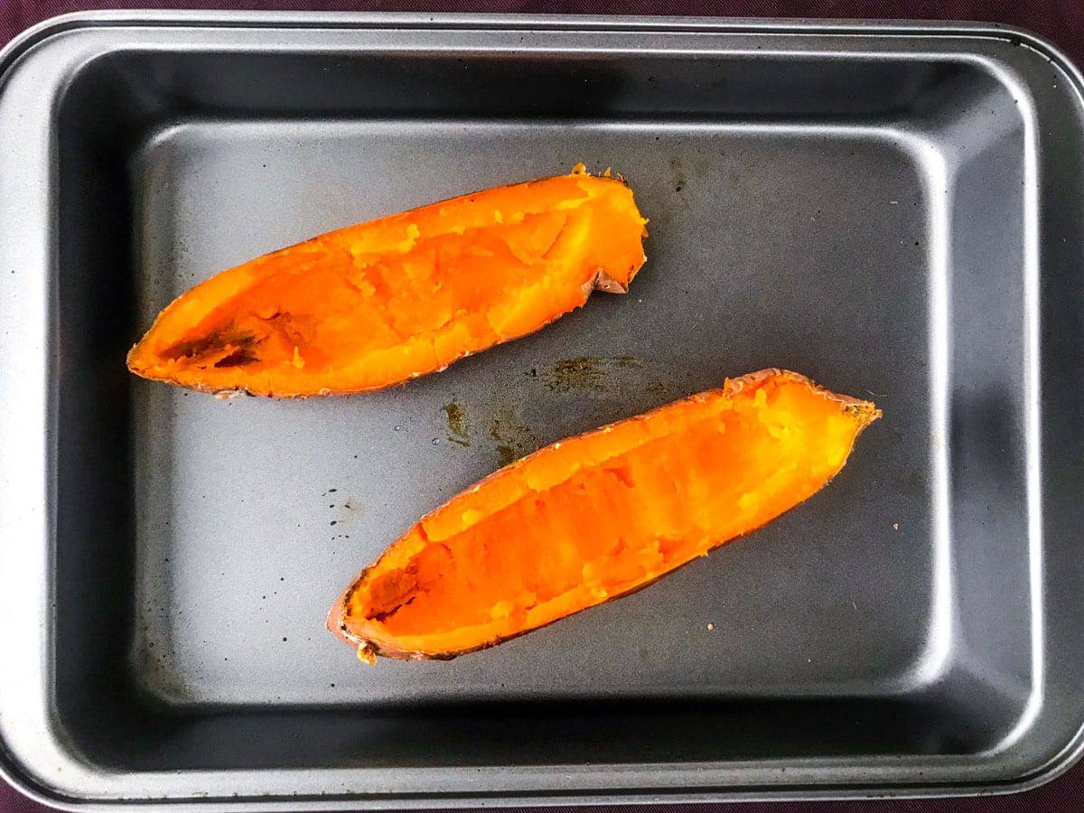 top down view of two sweet potato halves in a deep oven dish