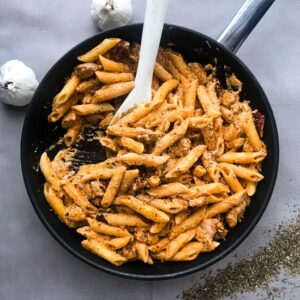 Sundried tomato pasta with chicken in a skillet.