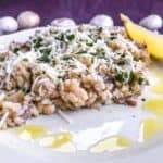 Creamy truffled mushroom risotto with a lemon wedge on a plate on a purple surface