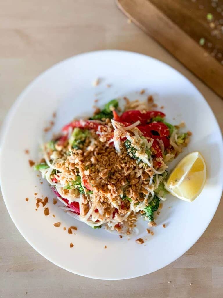 top view of vegetarian pad thai topped with crushed peanuts and lemon