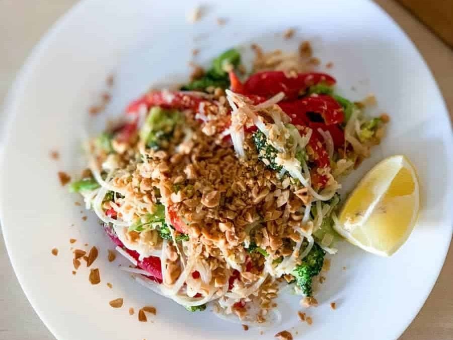 top view of vegetarian pad thai topped with crushed peanuts and lemon