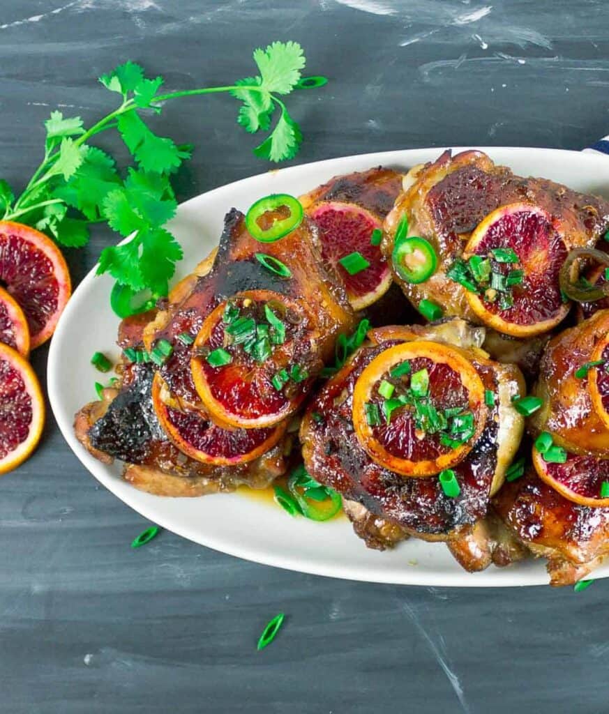 chicken topped with blood orange slices on a white plate