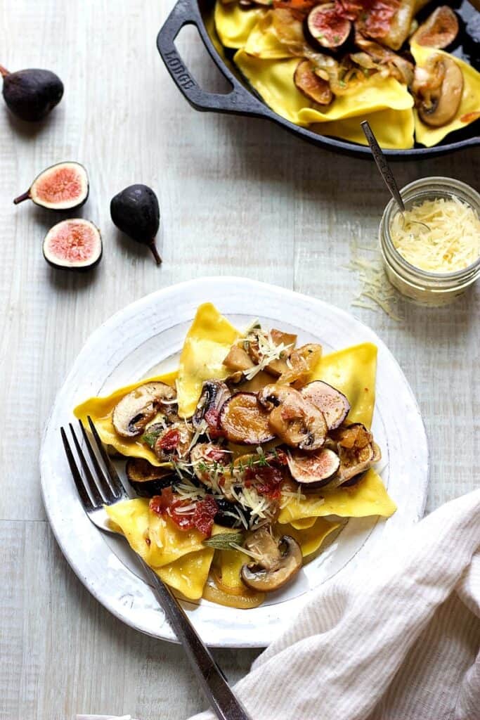 a plate full of ravioli with mushrooms and figs