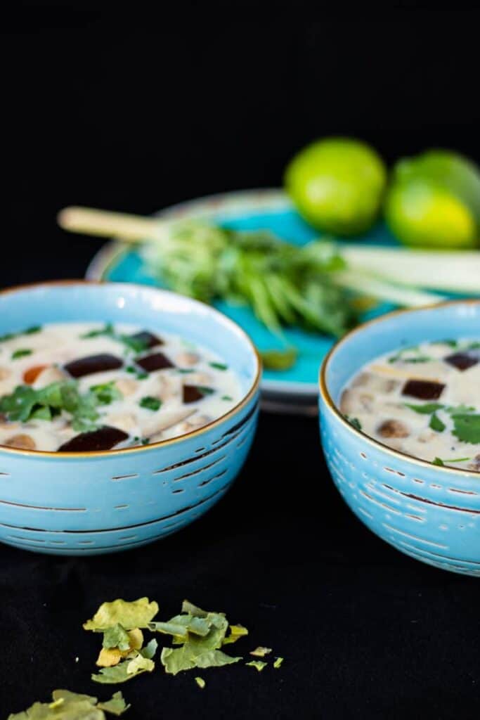 two blue bowls of thai ginger coconut soup on a black surface