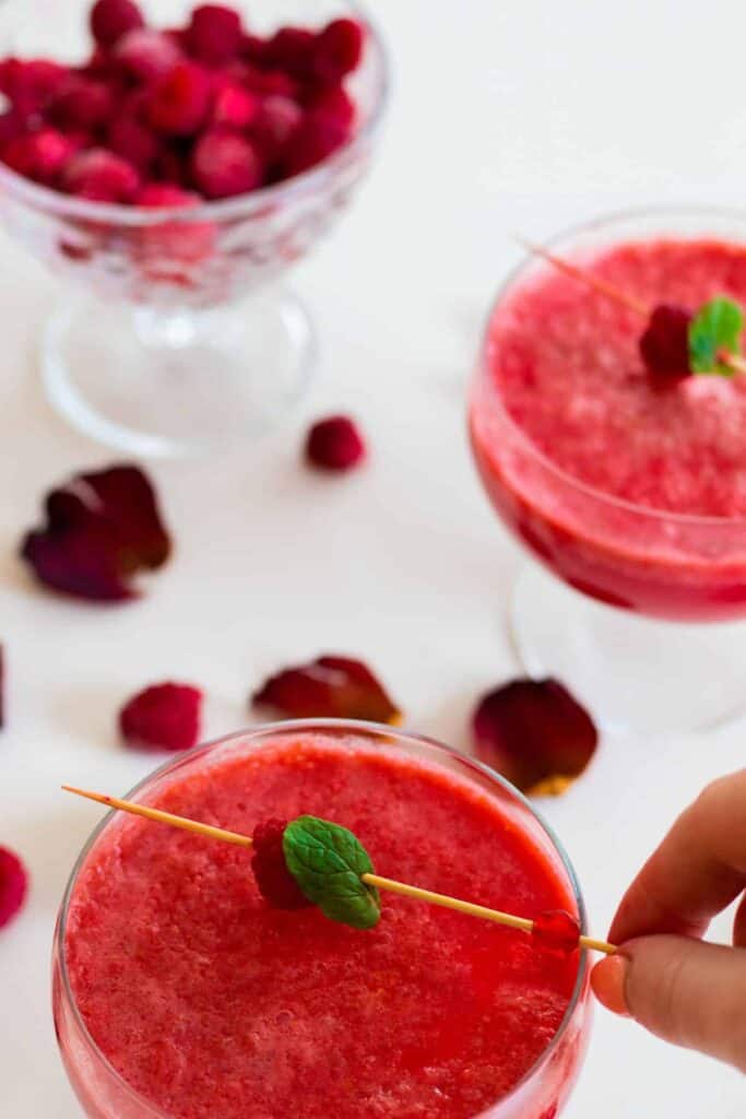 a glass of sparkling raspberry grapefruit mocktail  being decorated