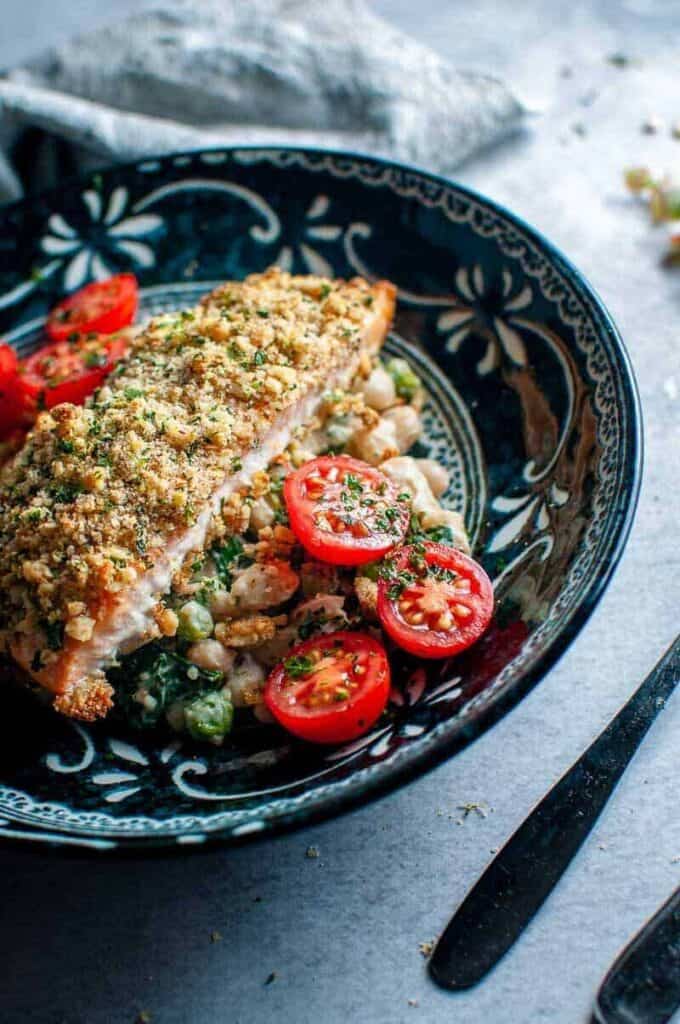 walnut crusted salmon in a dark bowl with cherry tomatoes