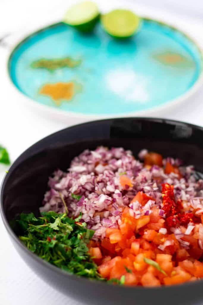 side view of chopped tomatoes, red onion, chili and cilantro for pico de gallo