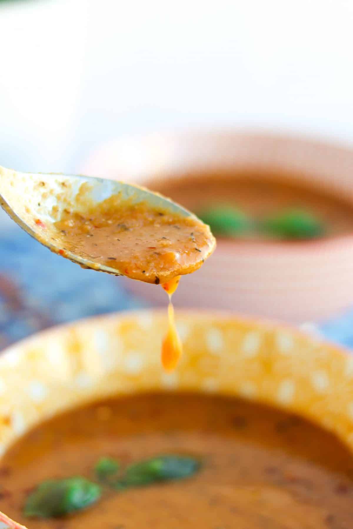 two bowls of vegan lentil soup and a spoonful of lentil soup