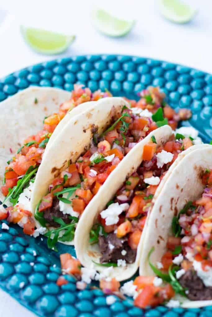 four vegetarian tacos with black beans, feta cheese and pico de gallo