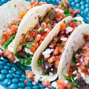 close-up of four vegetarian tacos with black beans, feta cheese and pico de gallo