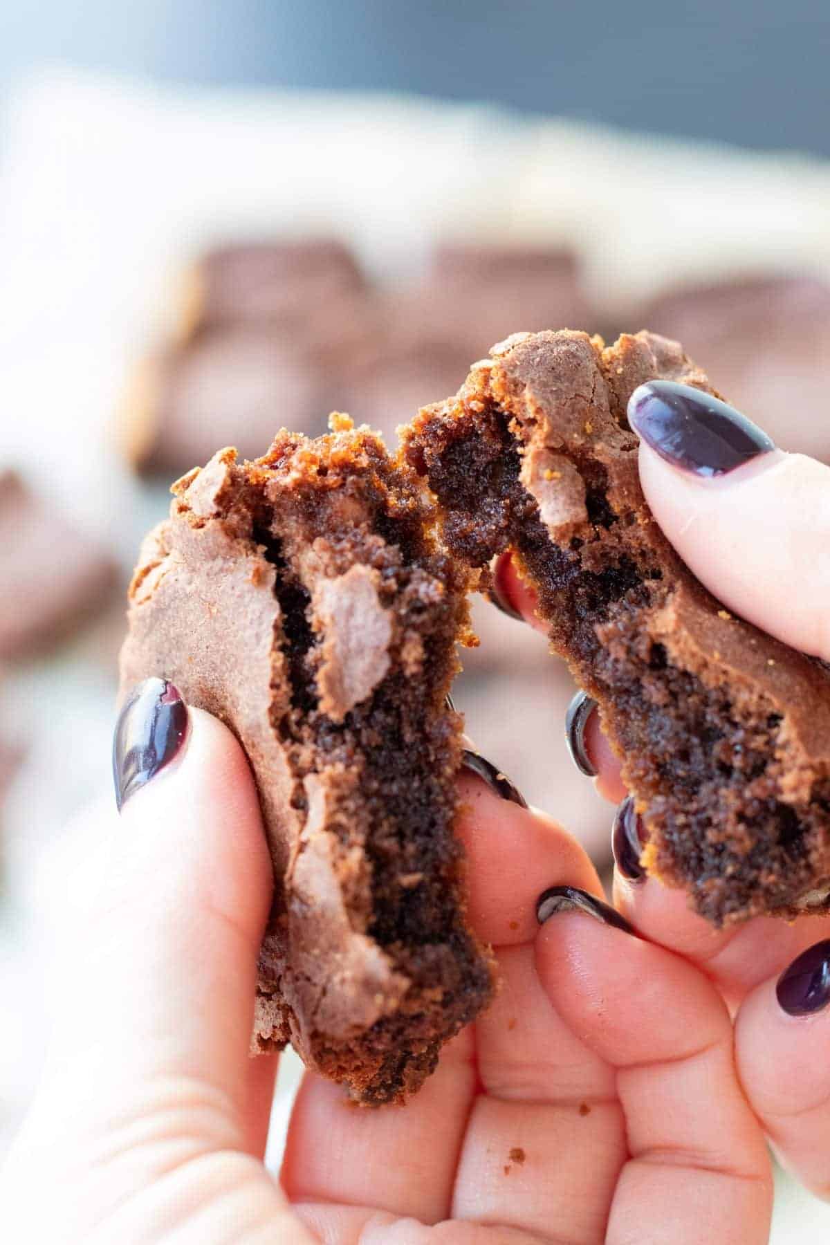 a brownie with cocoa powder being broken apart.