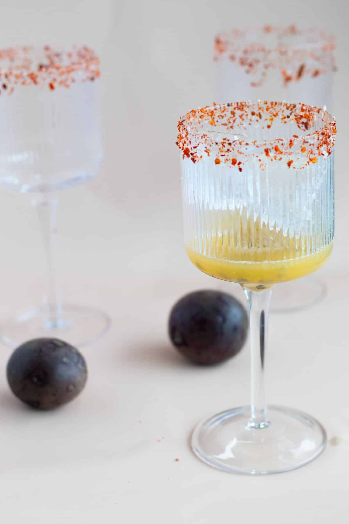 passion fruit and lime juice with ice cubes in a glass rimmed with sea salt and chili flakes
