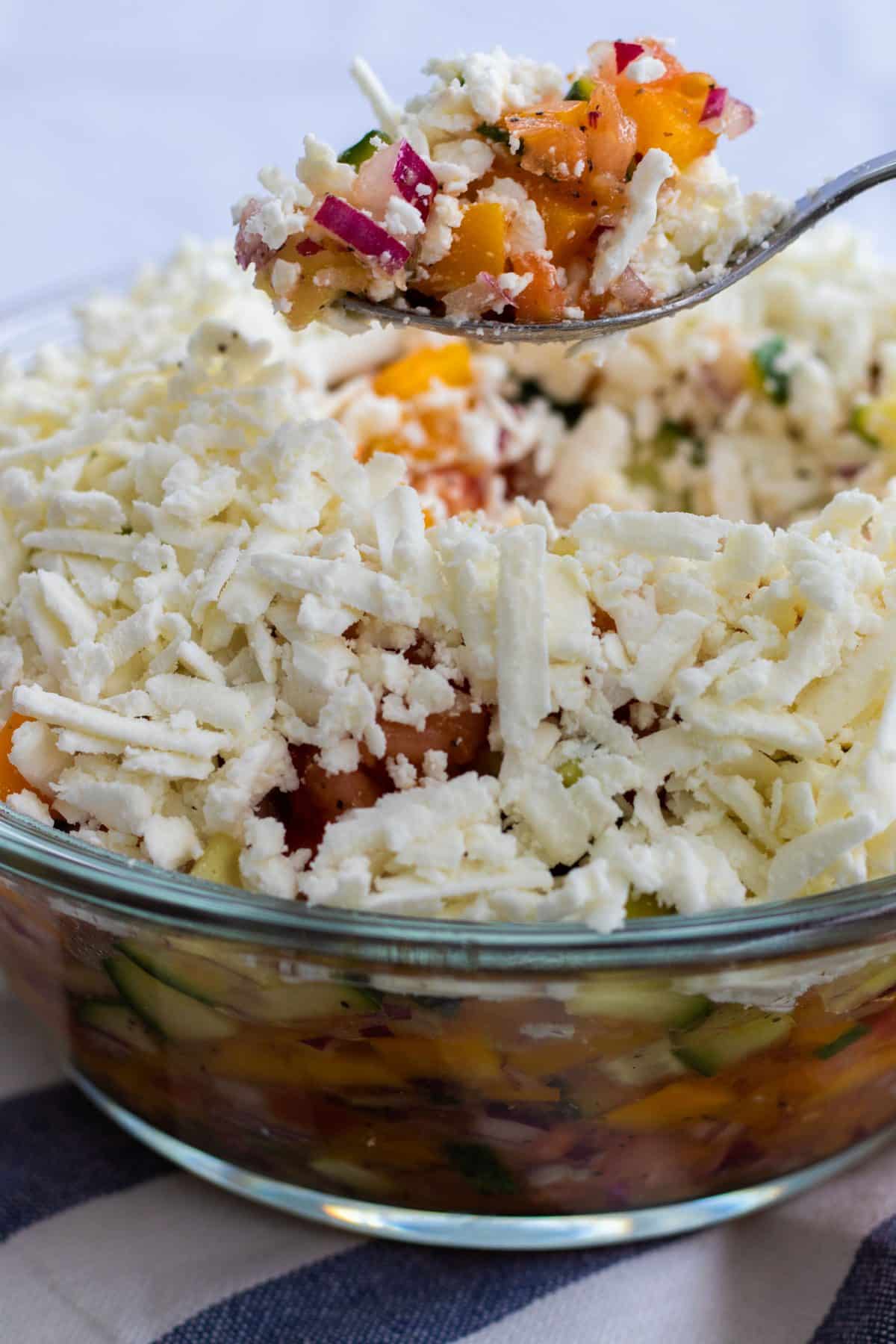 a spoonful of shopska salad being lifted up out of the bowl