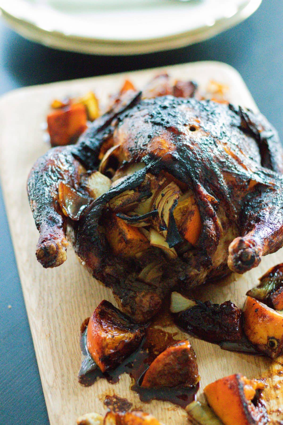 a roasted whole chicken with oranges and onions on a wooden board