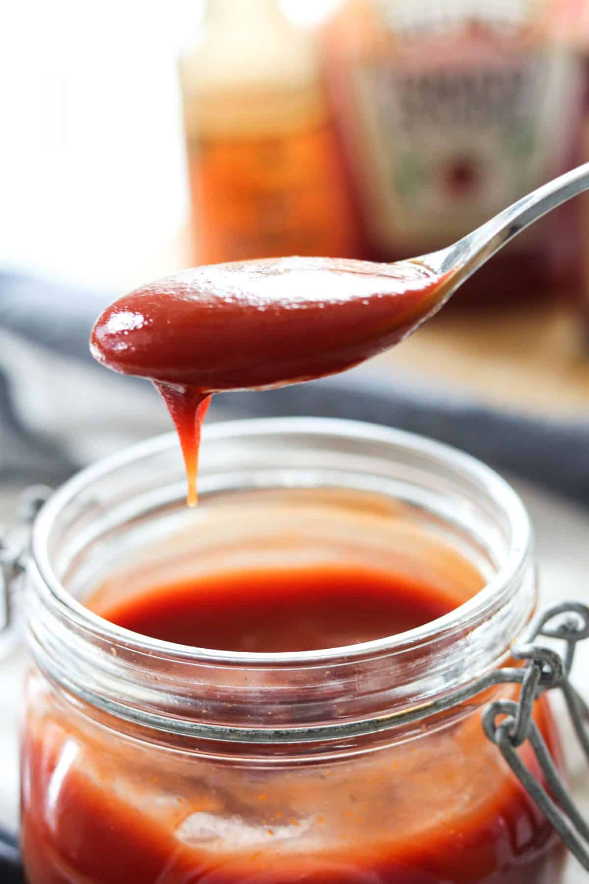 a spoonful of barbecue sauce over a jar of barbecue sauce