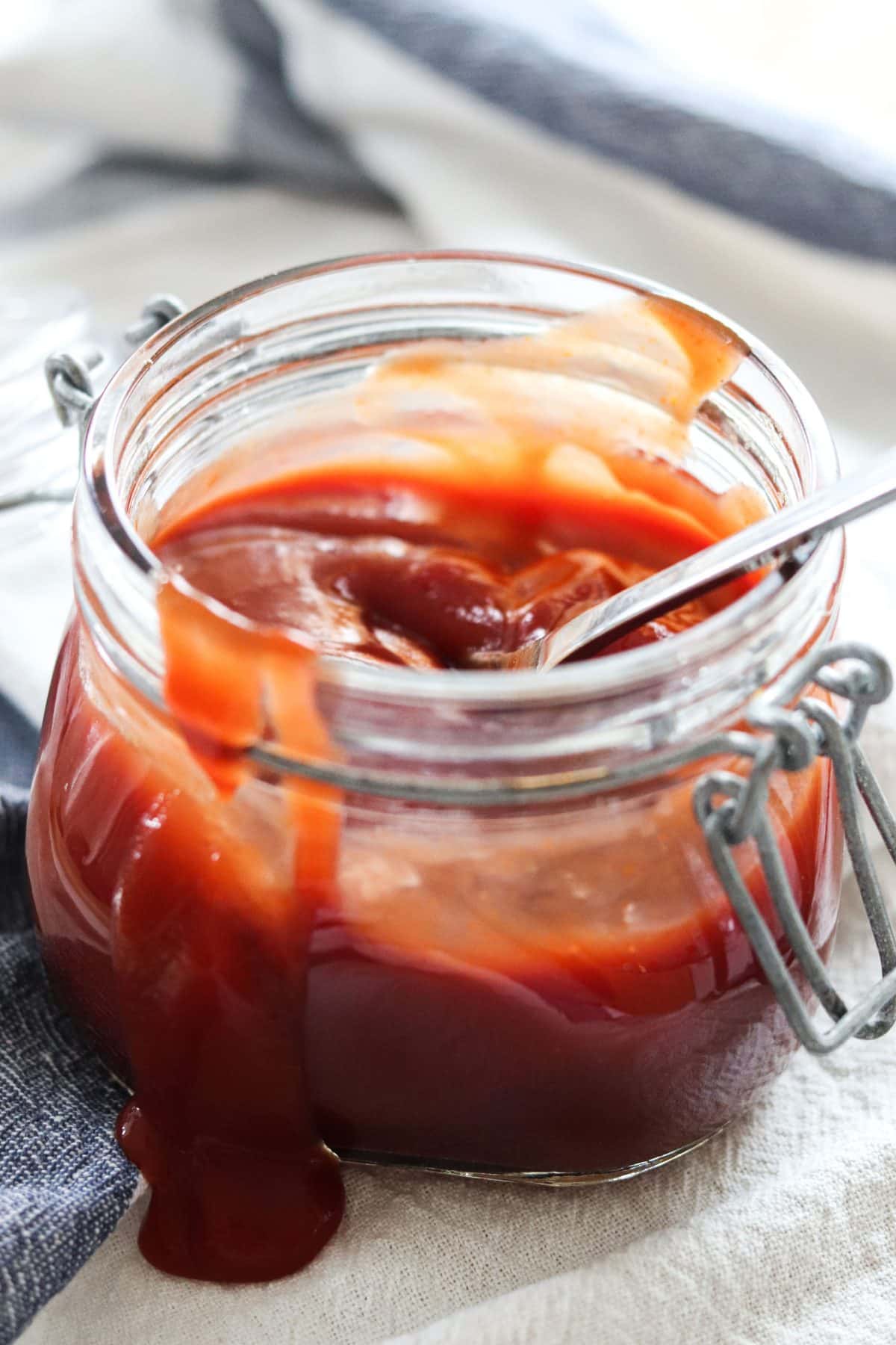 barbecue sauce in a jar with a spoon, with barbecue sauce spilled on the side