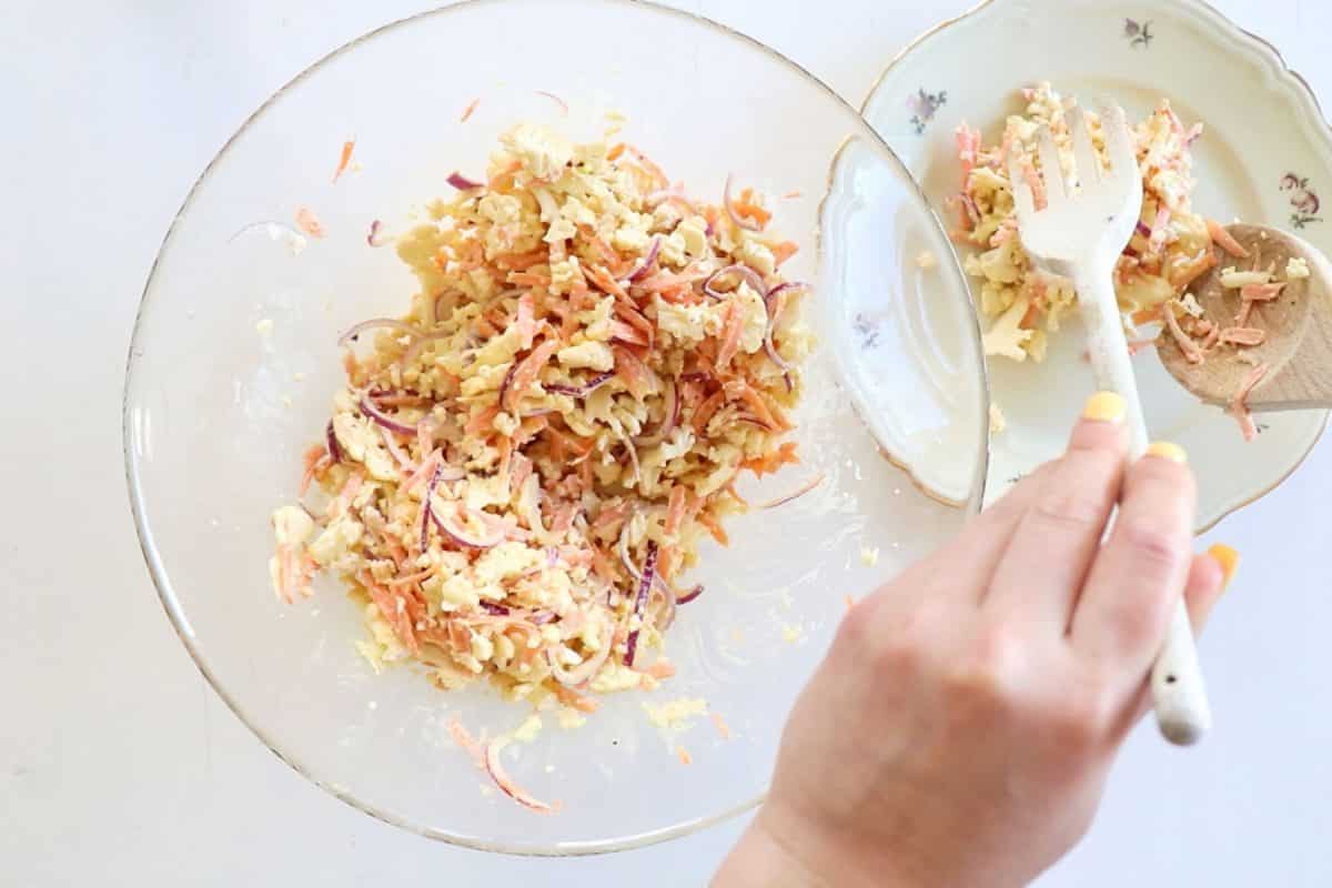 top view of serving raw cauliflower salad from a bowl to a small plate