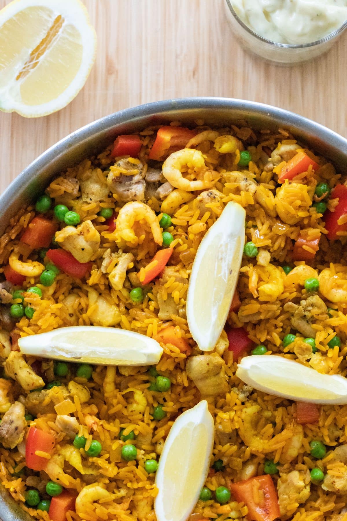 close up top down photo of paella with lemon wedges