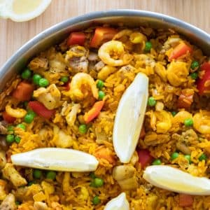 close up top down photo of paella with lemon wedges