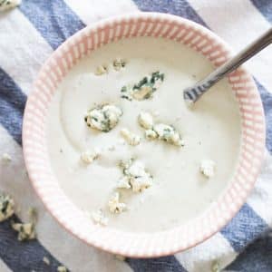 top view of a pink bowl with blue cheese sauce and blue cheese crumbles