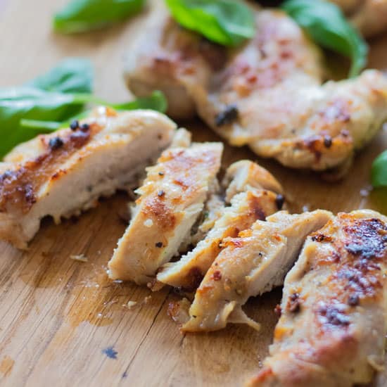 closeup of sliced grilled chicken with basil leaves