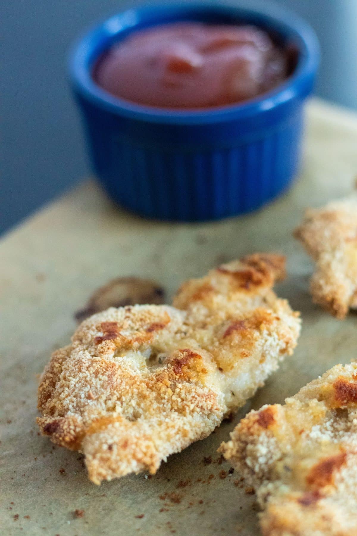 closeup of chicken tenders in front of a small blue bowl with barbecue sauce