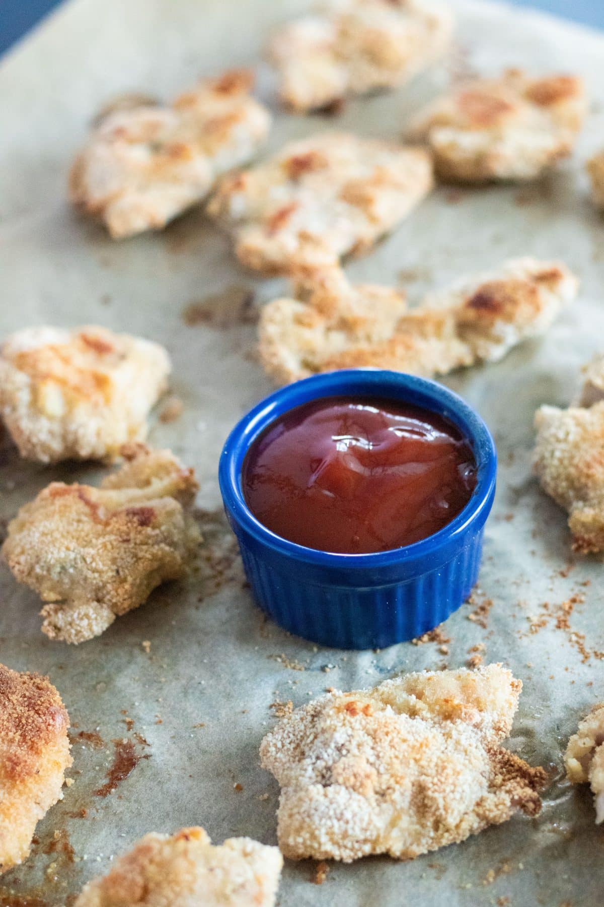 closeup of chicken tenders and a small blue bowl with barbecue sauce