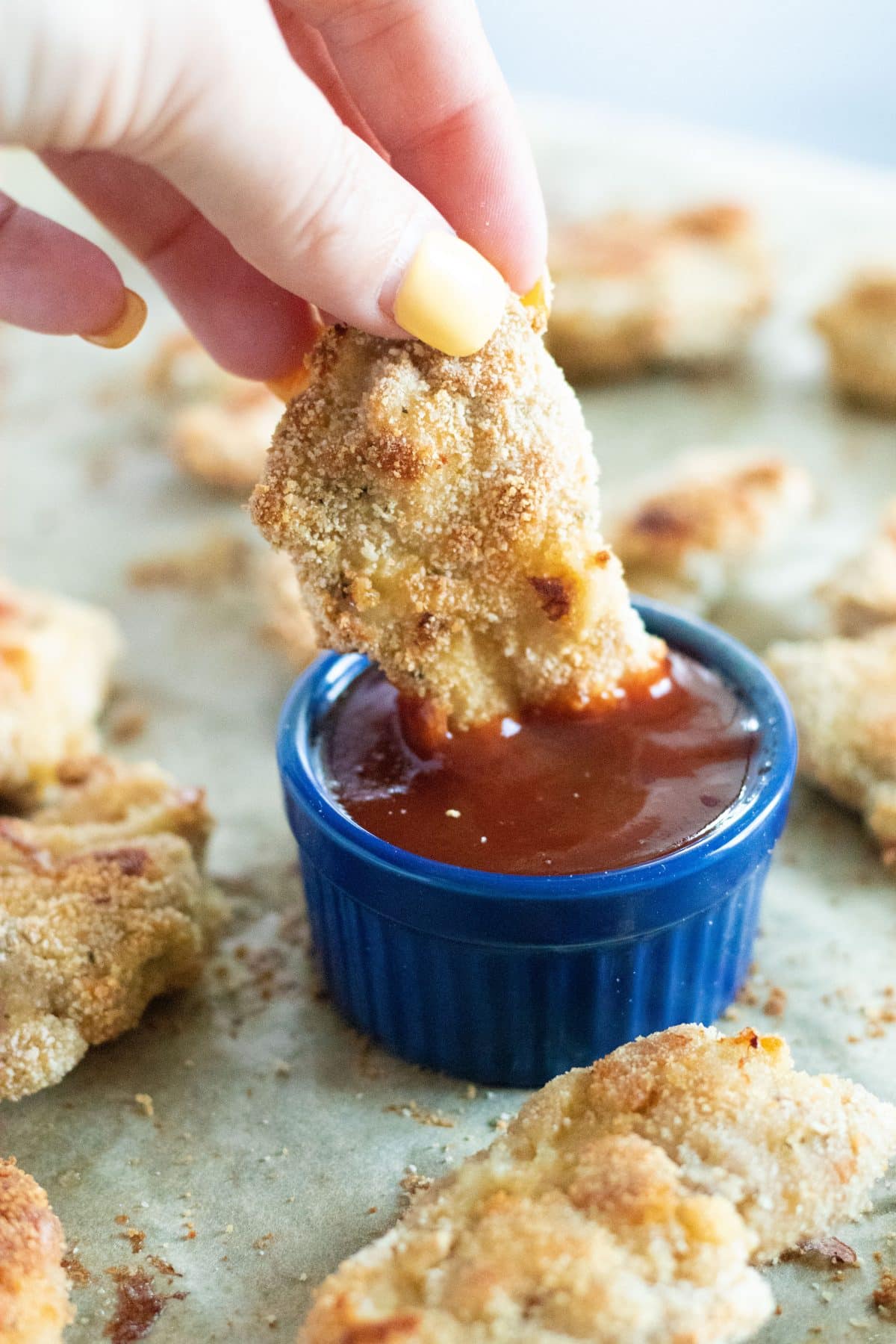 side view of a chicken tender being dipped into barbecue sauce