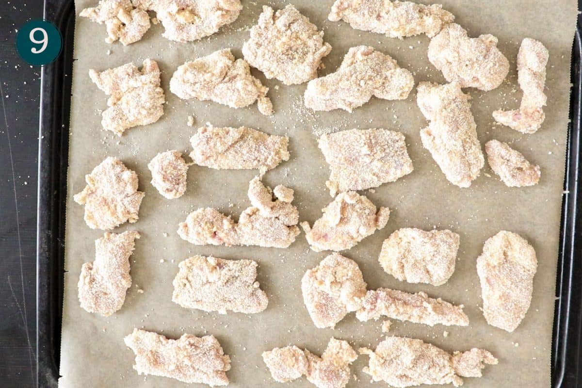 top down shot of breaded chicken tenders on an oven tray, before baking