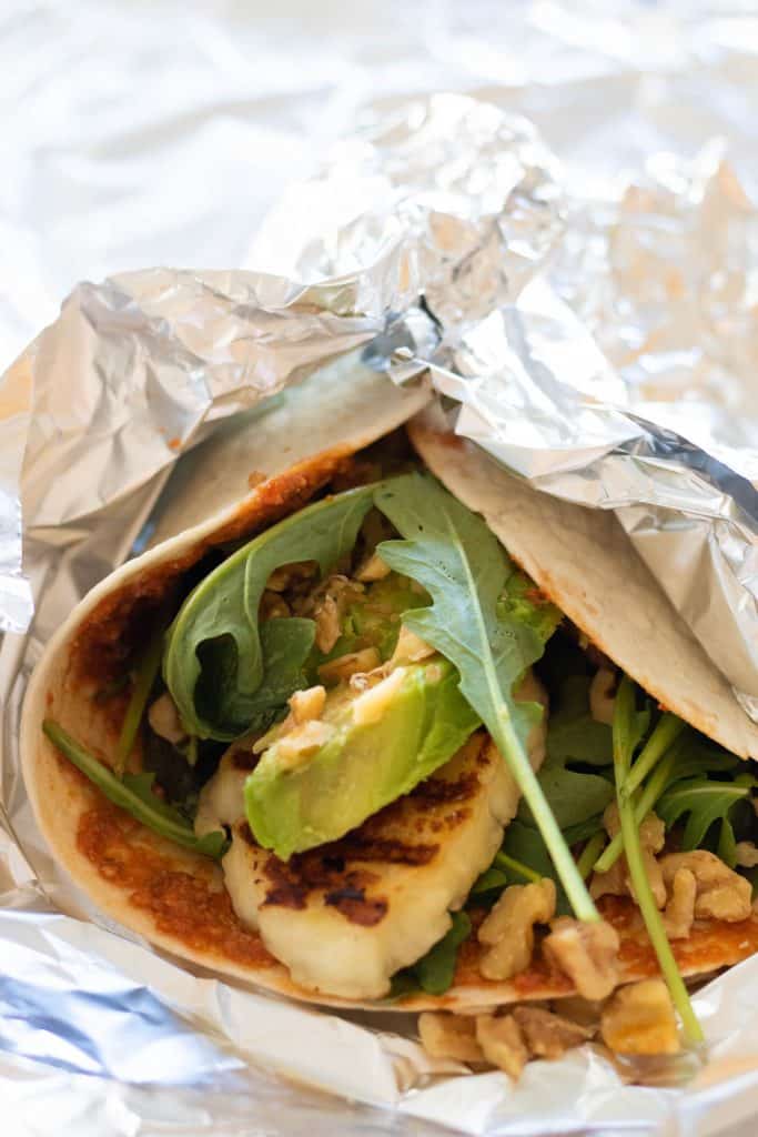 close up of wrap with halloumi, avocado and arugula in aluminium foil