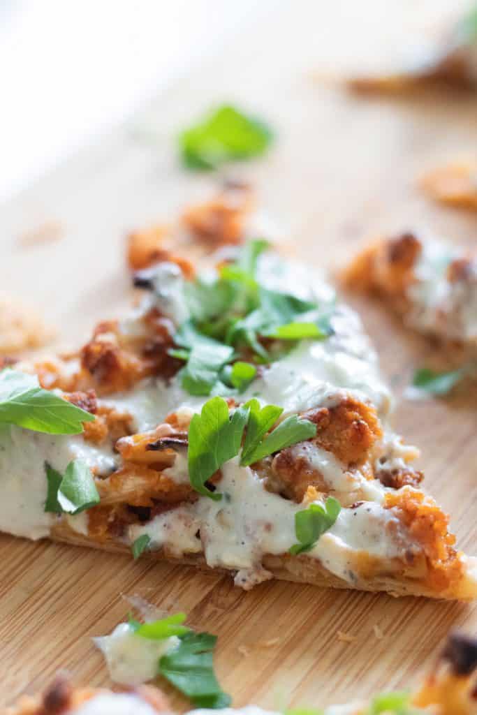 closeup of a slice of puff pastry pizza with buffalo cauliflower and blue cheese sauce