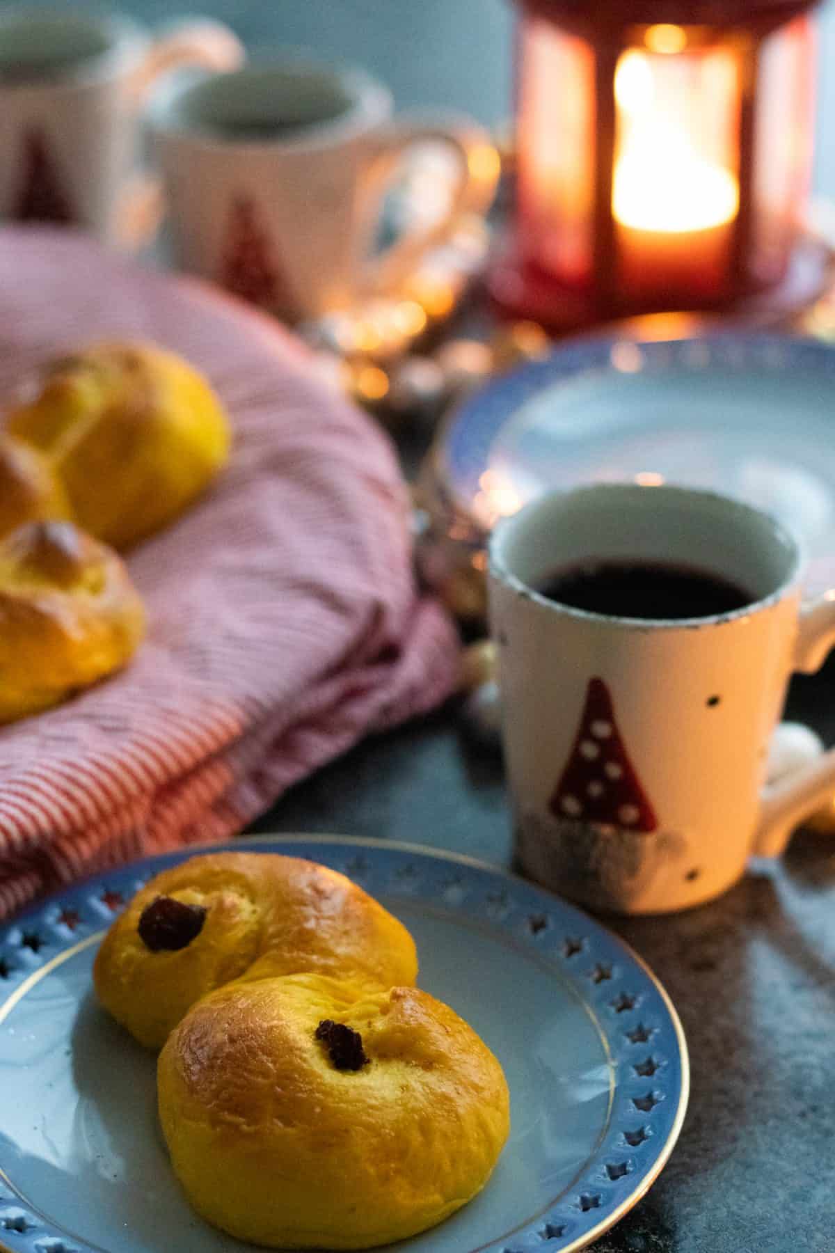 a Swedish saffron bun on a plate in front of a cup of glögg.