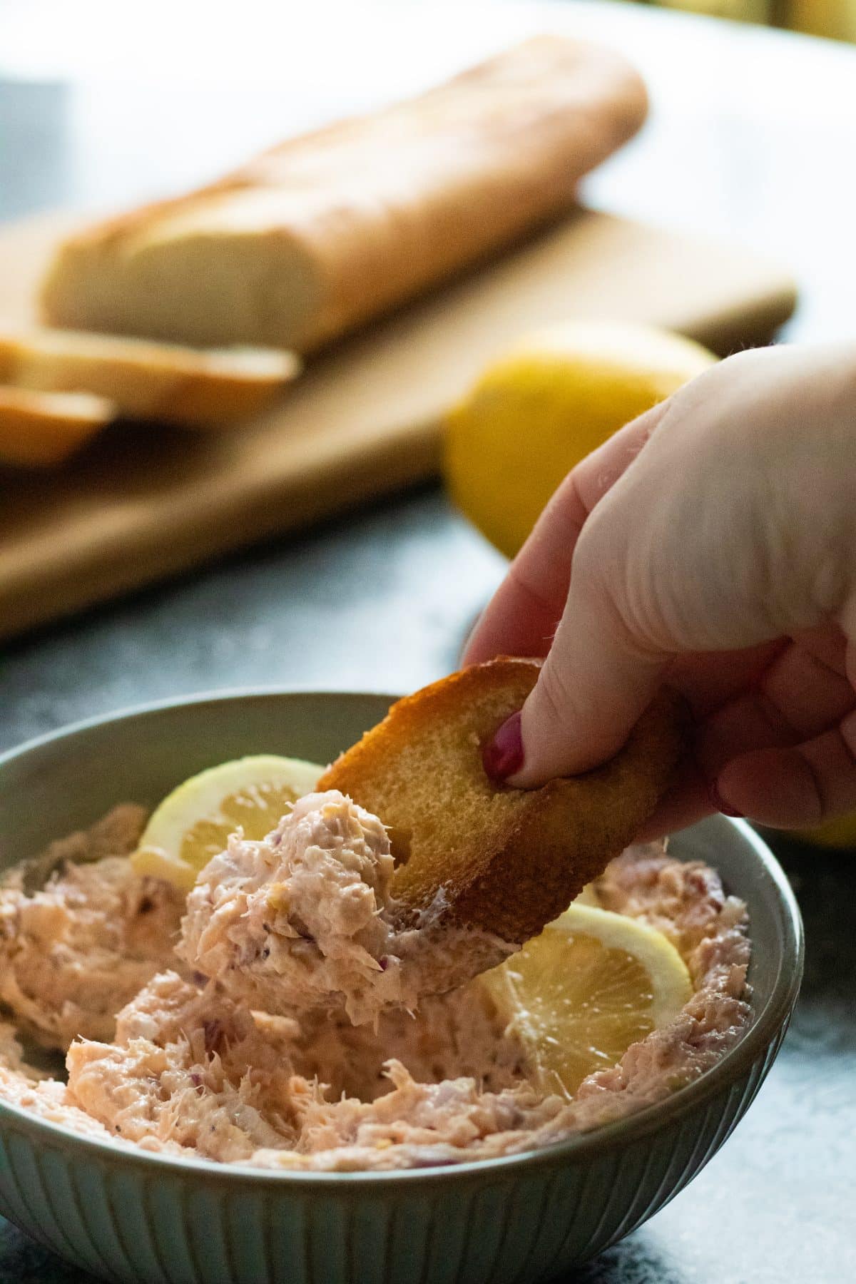 a piece of bread being dipped in hot smoked salmon pâté