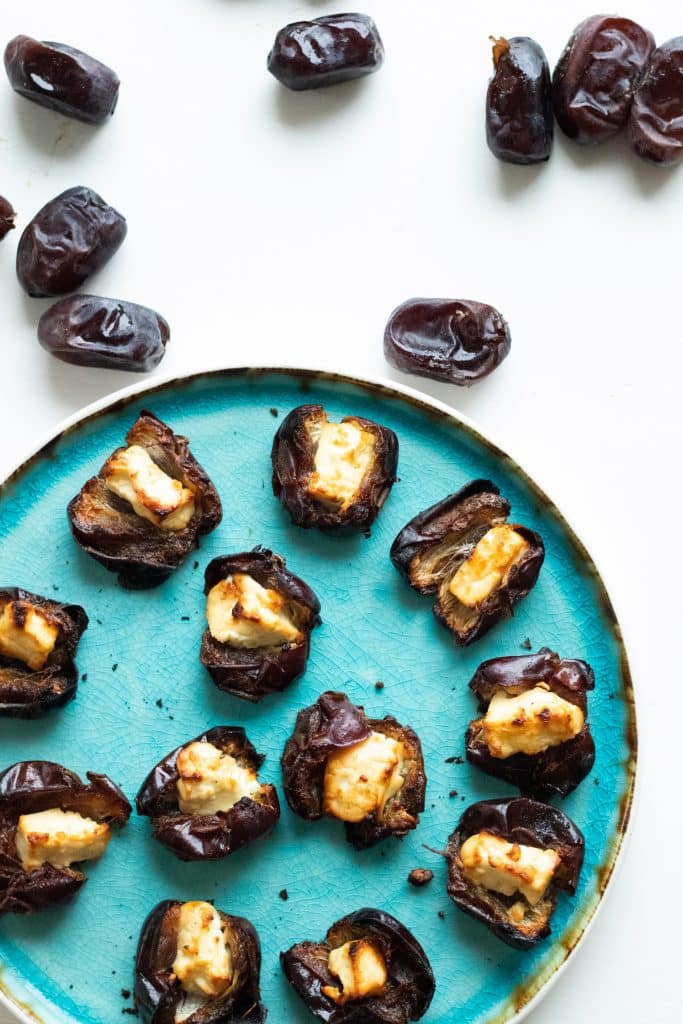 top down view of stuffed dates with feta cheese on a turquoise plate