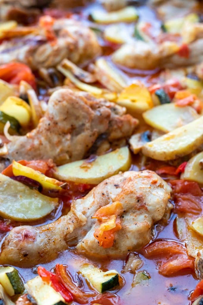 closeup of oven baked drumsticks with veggies and sauce