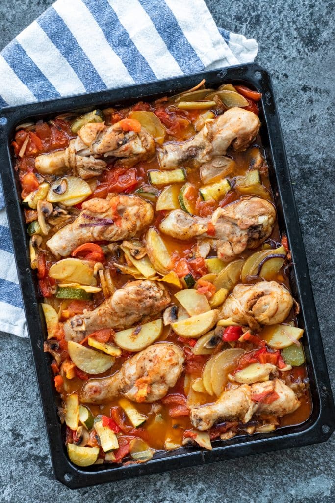 top down picture of finished oven tray with oven baked drumsticks with veggies and sauce