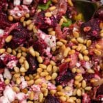 closeup of roast beetroot salad with feta cheese topped with pine nuts
