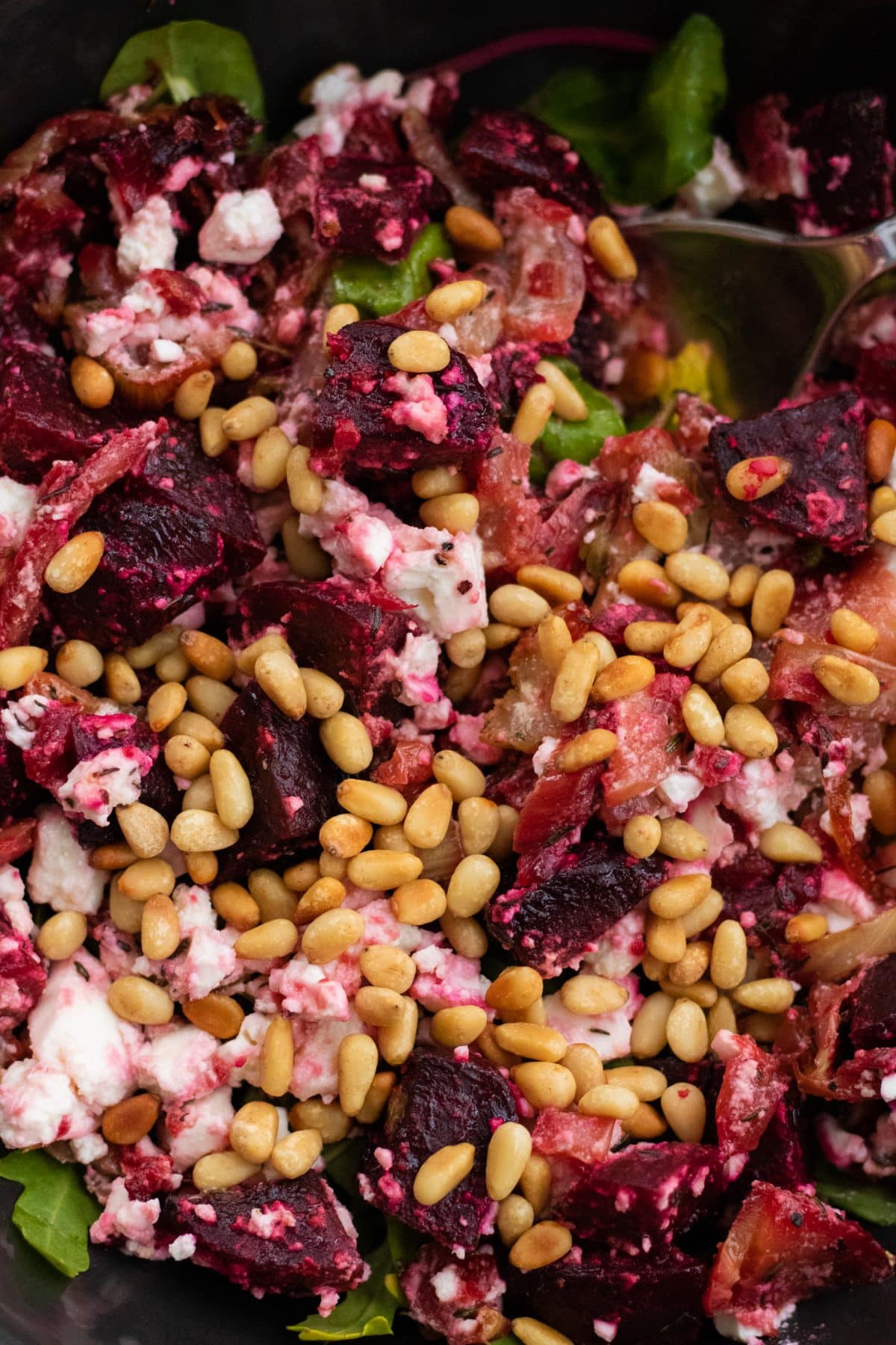 closeup of roast beetroot salad with feta cheese topped with pine nuts.