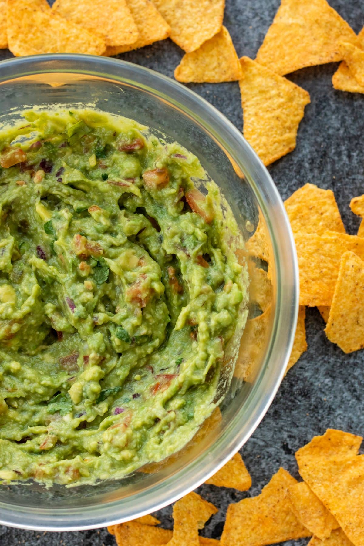 top down view of a bowl of guacamole surrounded by tortilla chips