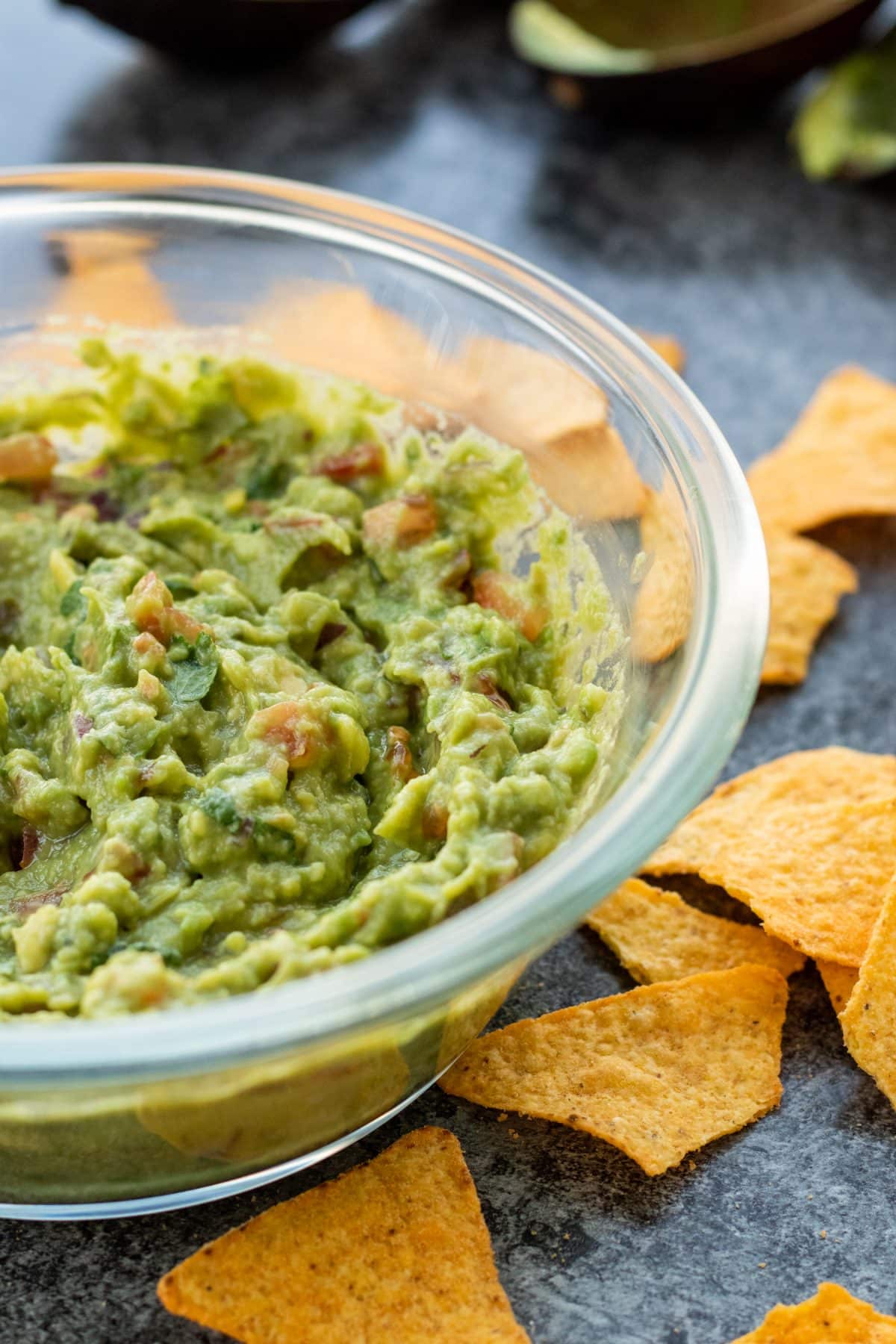 side view of a bowl of guacamole with tortilla chips on the side