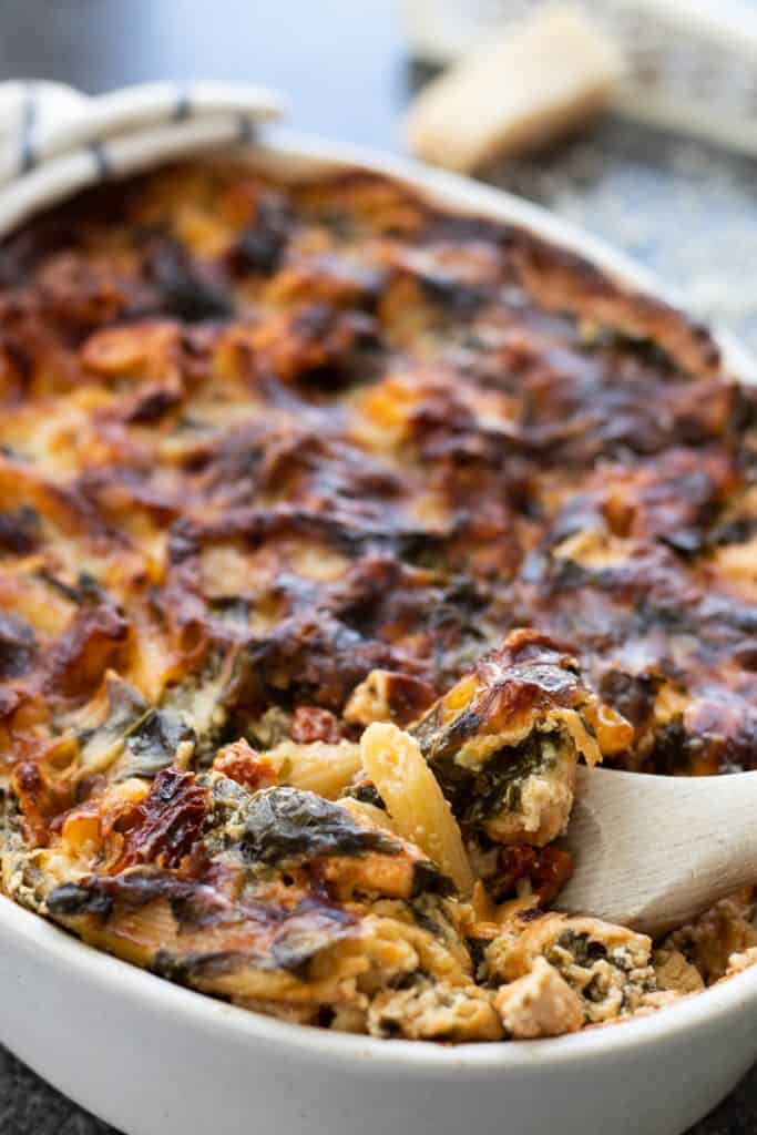 a spoonful of pasta bake being taken from a dish full
