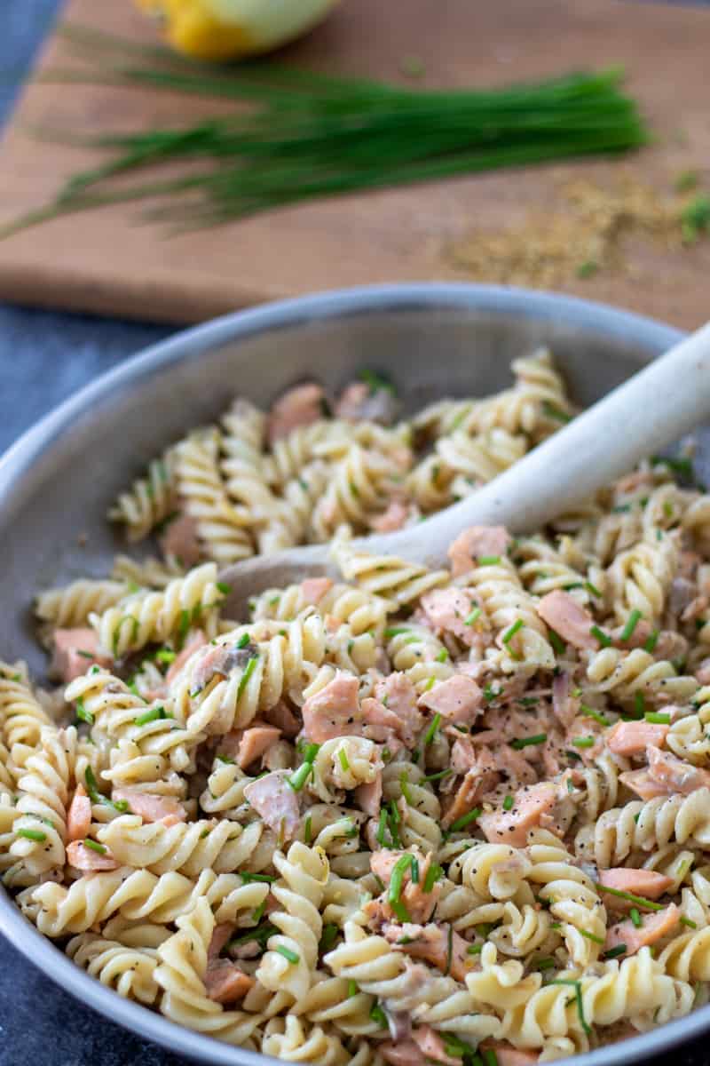 a pan full of salmon creme fraiche pasta with chives in the background