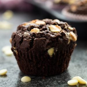 side view of a double chocolate chip muffin in front of a muffin tray full