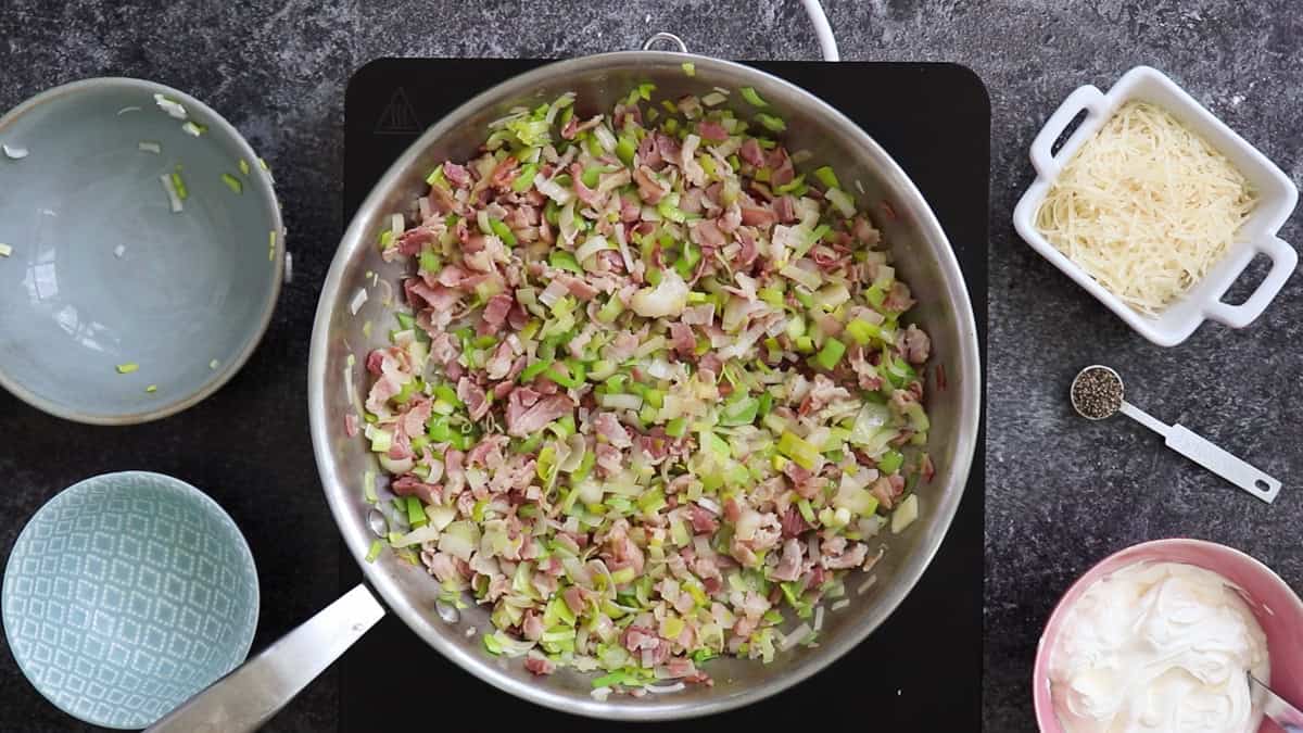 Cooked bacon and chopped leeks in a pan, to make creme fraiche carbonara.