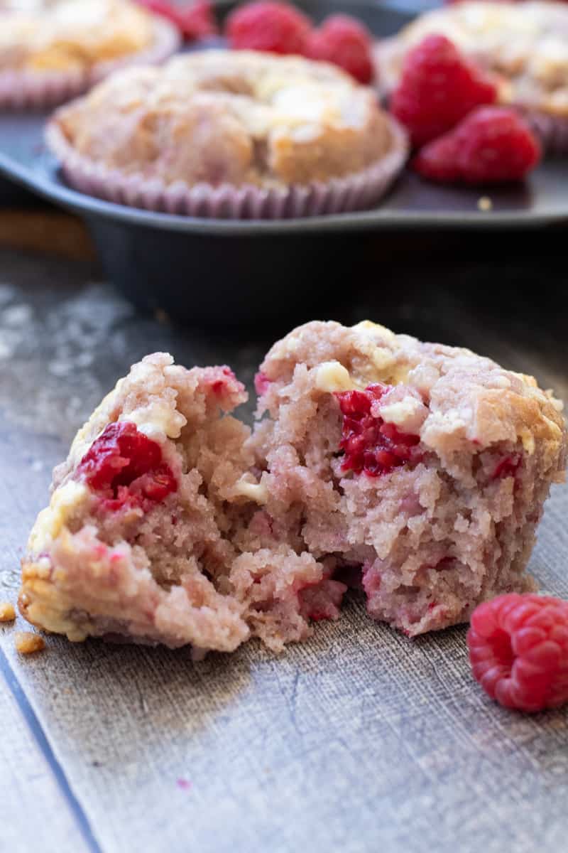side view of a raspberry white chocolate muffin broken in two