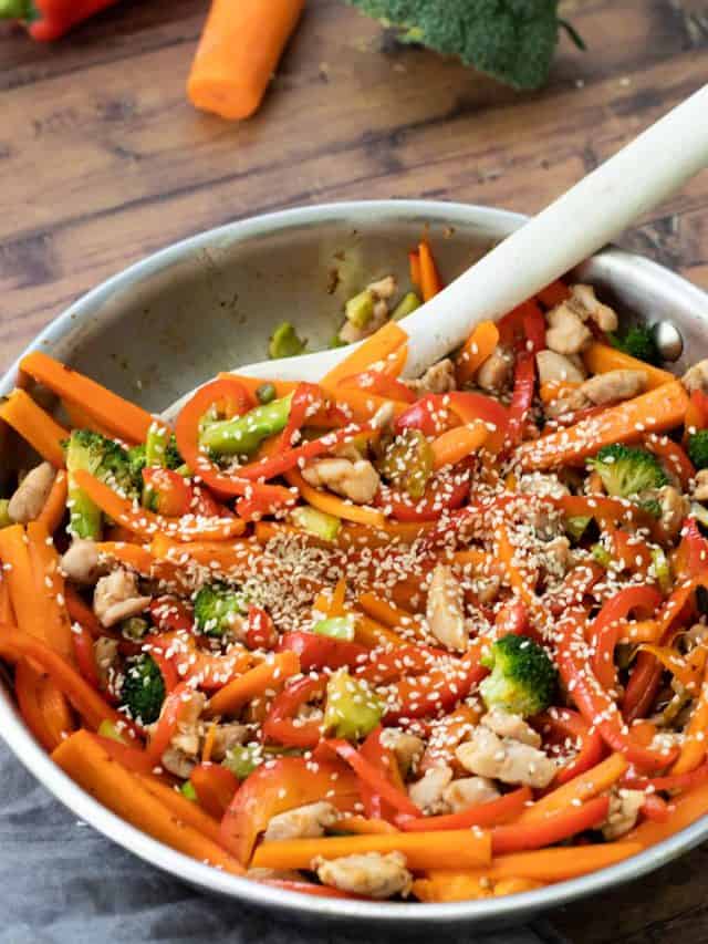 a pan full of chicken teriyaki stir fry with a wooden spoon in it