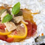 an opened foil pack after cooking, topped with basil.
